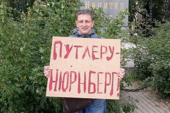<em>Григорий Северин в одиночном пикете. За этот же плакат в январе 2021 года его <a href="https://ryhieyug---mekodxpr-bsccljbcrq-ez.a.run.app/express-news/2021/01/20/voronezhca-arestovali-iz-za-odinochnogo-piketa-v-podderzhku-navalnogo"><u>арестовали</u></a> на пять суток (ч. 8 ст. 20.2 КоАП РФ) / Фото: Свободные Люди Воронежа</em>